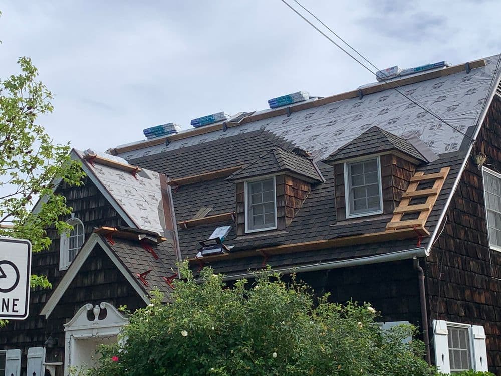 Newly installed roof shingles and underlayment on a two-story house during renovation.